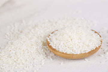 Rice grains closeup in a wooden bowl on a white background.
