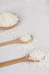 Rice grains closeup in a wooden spoon on a white background.