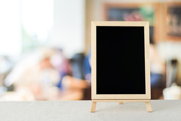 Blank chalkboard standing on sack tablecloth over blur restauran