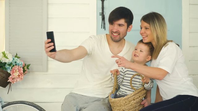 Father of happy family make selfie with his wife and little son in front their home door