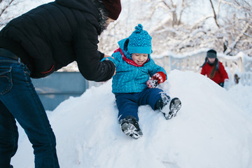 Fototapeta na wymiar warmly dressed boy riding on a snowy hill