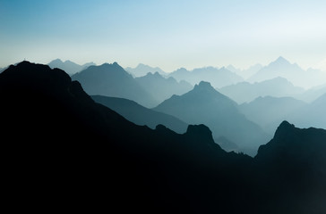 Spectacular blue and cyan mountain ranges silhouettes. Summit crosses visible.