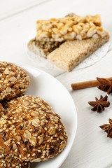 Oatmeal cookies with sesame, nuts, cinnamon and star anise on a white wooden table, vertical
