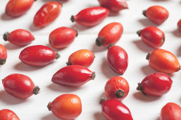 Close-up shot od rosehip berries on a wooden table, light toning