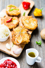 Food. Potato Pancakes on Breadboard with Ingredients on Wooden Background