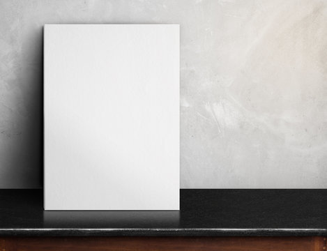 Blank White paper poster on black marble table at grey concrete
