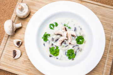 Top View Mushroom Soup with Raw Champignons on Breadboard