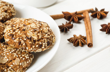 Oatmeal cookies with sesame, nuts, cinnamon and star anise on a white wooden table, close-up shot