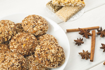Oatmeal cookies with sesame, nuts, cinnamon and star anise on a white wooden table, toned