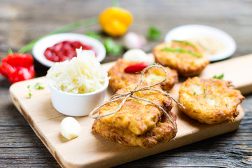 Fried Potato Pancakes on Breadboard with Ingredients on Wooden Background