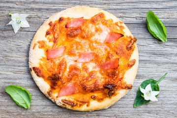 Top View Small Margarita Pizza with Ham, Cheese and Basil Leaves on Wooden Background
