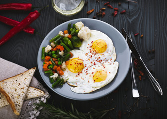 Delicious, tasty fried and mix vegetables on a plate. Top view of a wooden background. Close-up
