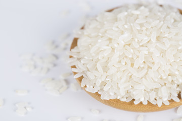 Rice grains closeup in a wooden bowl on a white background.