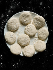 Floured homemade cookies prepared for baking, top view, vertical