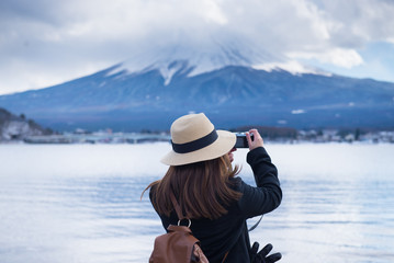 Fototapeta na wymiar Lady tourist is taking photography of Mt. Fuji at Lake Kawaguchi in Japan.