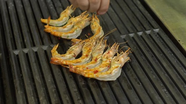 closeup large shrimp fry on the grill sprinkle with spices blows smoke in slow motion