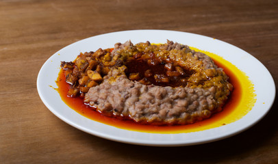 A plate of mashed beans with red palm oil stew and fried plantain