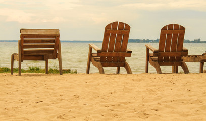 Fototapeta na wymiar Wooden chairs at lake beach, summer holiday concept
