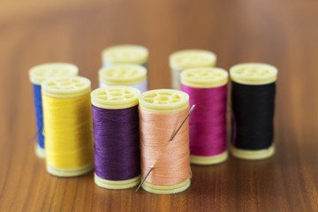Spools of colorful silk thread on wooden background