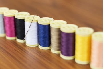 Spools of colorful silk thread on wooden background