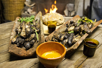 Calçots in a tires with bread, romesco sauce and wine front of a fire.