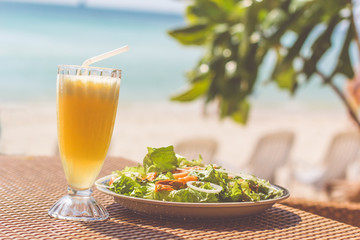 Seafood salad, orange fresh juice on the table near sea