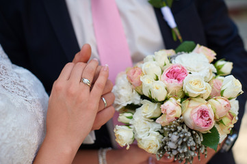 Obraz na płótnie Canvas groom holds his brides hand and a wedding bouquet