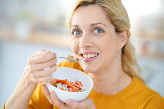 Portrait of blond middle-aged woman eating cereals