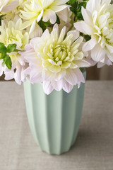 Bouquet of yellow dahlia flowers in blue ceramic vase.