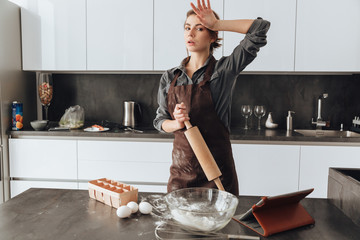 Woman standing in kitchen and cooking the dough