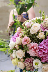 Woman making floral arrangement with carnation, eustoma and hort