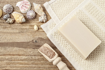 Tiny shells and scoop of sea salt on wooden background.