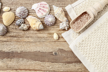 Fototapeta na wymiar Tiny shells and scoop of sea salt on wooden background.