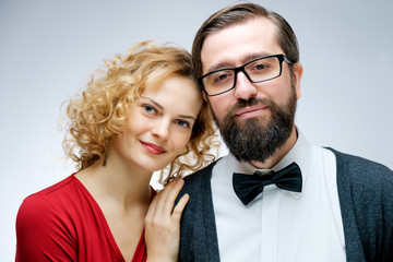 Portrait of young couple in love posing at studio dressed in classic clothes