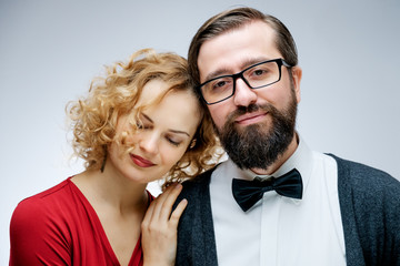 Portrait of young couple in love posing at studio dressed in classic clothes