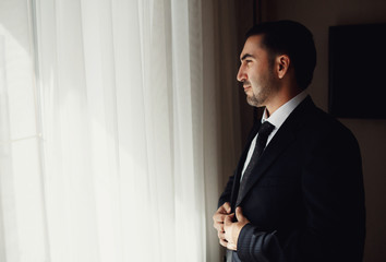 The groom standing near window