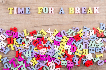 Text "Time for a break" of colored wooden letters on a wooden background