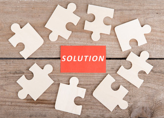 Jigsaw Puzzle Pieces with text "Solution" on wooden background