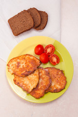 Potato pancakes with meat and tomatoes on green plate with rye b