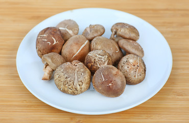 Shiitake mushroom on white plate against wood background