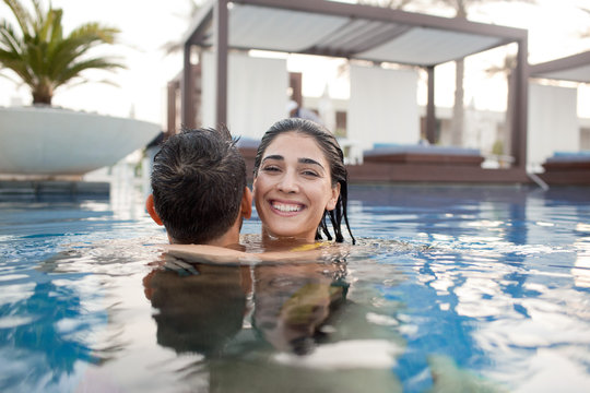 Expat couple embracing in swimming pool.