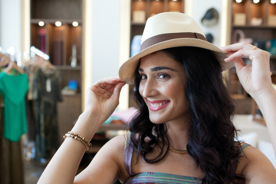 Woman trying on hat at boutique.