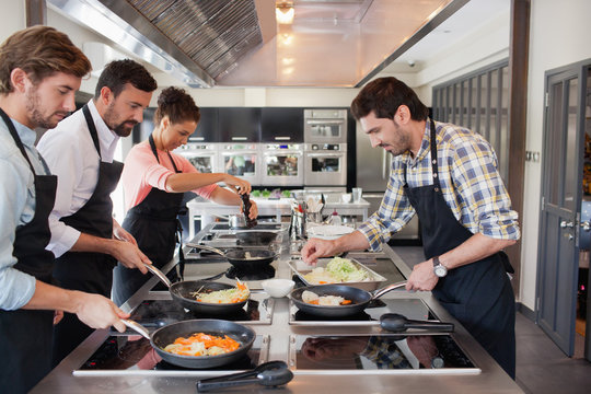 Chefs cooking food at kitchen.