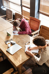 Concentrated young colleagues in office working with notebooks