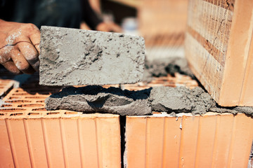Details of industrial bricklayer installing bricks on construction site