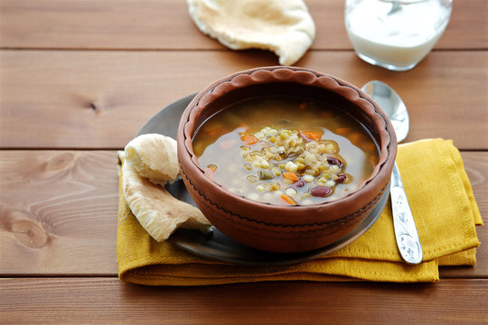 Soup with beans, lentils, peas and vegetables on wooden background