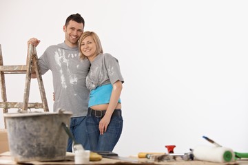 Happy couple standing front of painted white wall