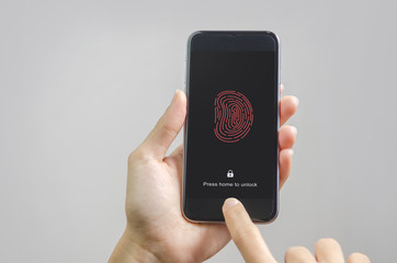 Female scanning fingerprint on smartphone, on gray background. Unlock mobile phone.