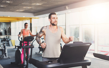 Young man in gym run on treadmill