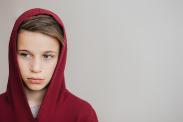 Young attractive boy in red hoodie looks away on a light background - 137070182